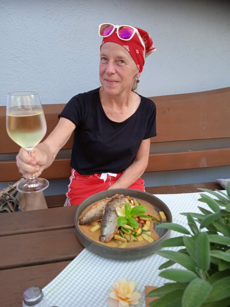 Marika Heinlein mit Weinglas vor einem Teller mit Fisch